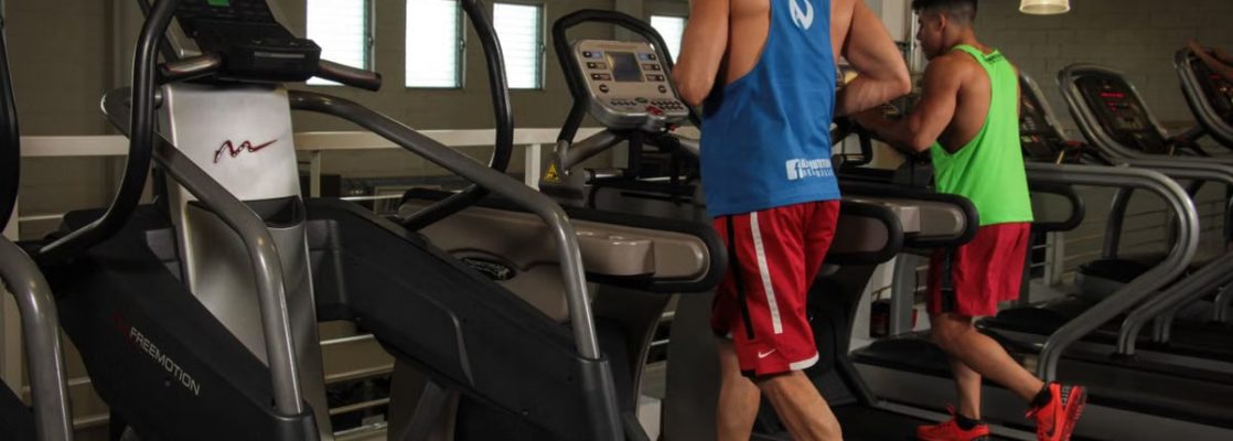 Two men running on treadmills in a modern gym, promoting fitness and health.